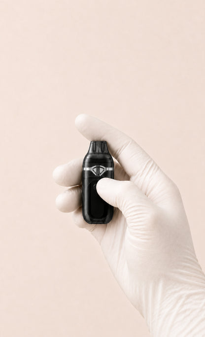 One gloved right hand holding compact Lumen dual-chamber empty disposable hardware while pressing the front selector.